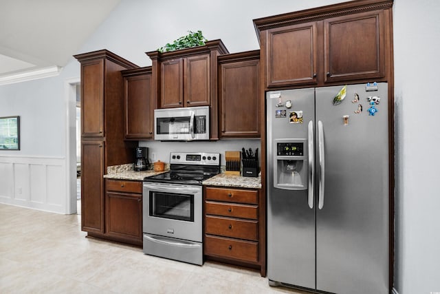 341 Bahama Dr, Murrells Inlet, SC 29576 - kitchen with stainless steel appliances, light stone counters, wainscoting, dark brown cabinets, and light tile patterned flooring