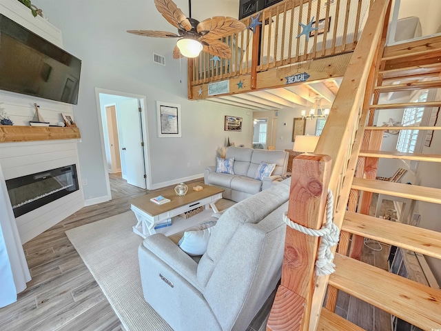 323 Wendover Ct Unit 10-A, Myrtle Beach, SC 29572 - living area with a towering ceiling, a glass covered fireplace, a chandelier, ceiling fan, and wood finished floors