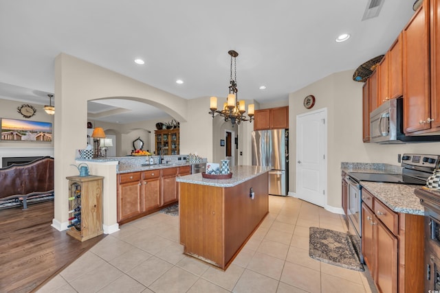 773 Wintercreeper Dr, Longs, SC 29568 - kitchen with stainless steel appliances, arched walkways, a chandelier, brown cabinets, and light stone counters