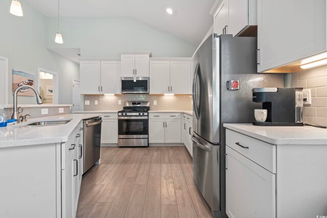 1178 Pyxie Moss Dr, Little River, SC 29566 - kitchen featuring appliances with stainless steel finishes, a sink, light wood finished floors, white cabinetry, and high vaulted ceiling