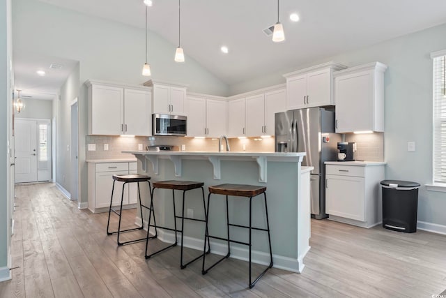 1178 Pyxie Moss Dr, Little River, SC 29566 - kitchen with stainless steel appliances, light countertops, light wood-style floors, white cabinetry, and lofted ceiling