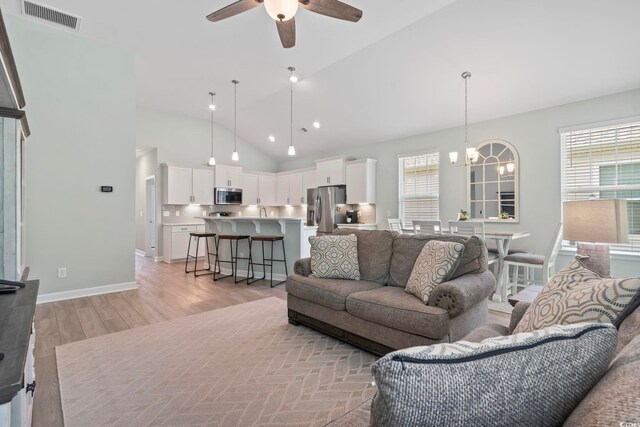 1178 Pyxie Moss Dr, Little River, SC 29566 - living room featuring a chandelier, lofted ceiling, light wood-type flooring, a ceiling fan, and baseboards