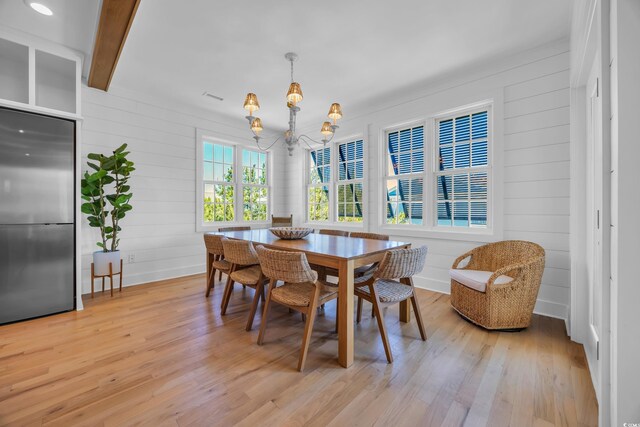 573 S Dunes Dr, Pawleys Island, SC 29585 - dining area featuring a chandelier, light wood-style flooring, and wood walls