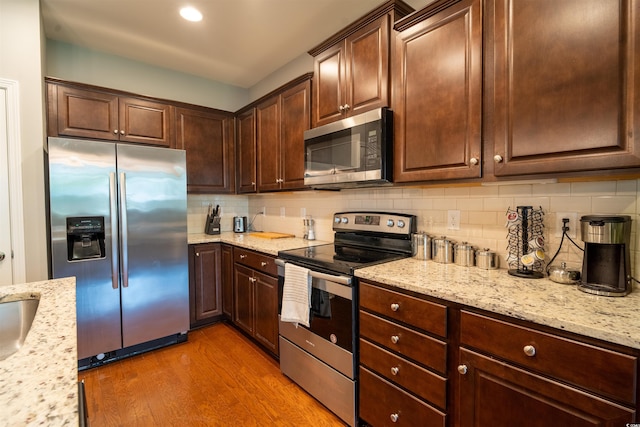 318 Castle Dr Unit 1443, Myrtle Beach, SC 29579 - kitchen with stainless steel appliances, wood finished floors, tasteful backsplash, light stone countertops, and dark brown cabinets
