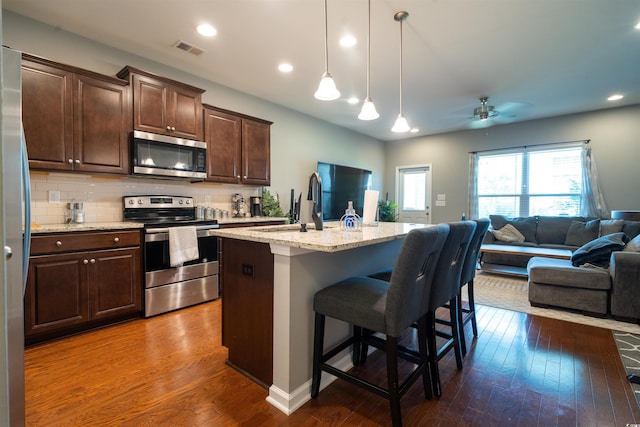 318 Castle Dr Unit 1443, Myrtle Beach, SC 29579 - kitchen featuring appliances with stainless steel finishes, dark wood-type flooring, open floor plan, a ceiling fan, and a kitchen bar