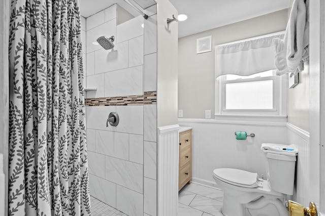 2006 S Ocean Blvd, North Myrtle Beach, SC 29582 - bathroom featuring toilet, a wainscoted wall, marble look tiles, a stall shower, and vanity