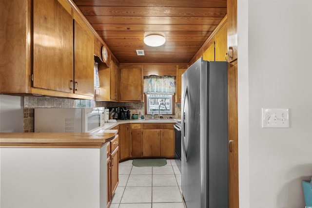 2006 S Ocean Blvd, North Myrtle Beach, SC 29582 - kitchen featuring freestanding refrigerator, a sink, white microwave, tasteful backsplash, and brown cabinetry