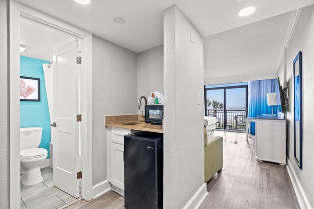 7200 N Ocean Blvd Unit 222, Myrtle Beach, SC 29572 - bar with black fridge, light wood-type flooring, and a textured wall