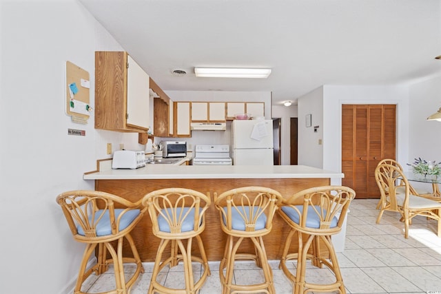 1890 Colony Dr Unit 17L, Surfside Beach, SC 29575 - kitchen featuring white appliances, under cabinet range hood, light countertops, a peninsula, and light tile patterned flooring