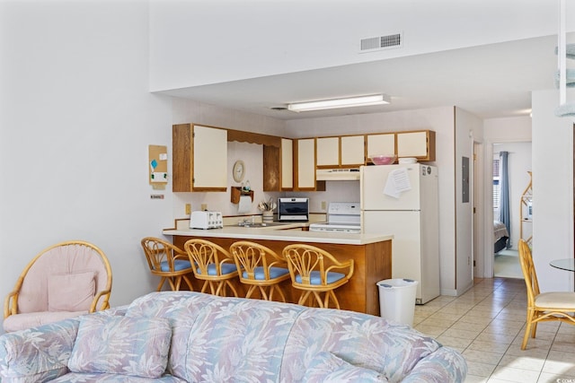1890 Colony Dr Unit 17L, Surfside Beach, SC 29575 - kitchen featuring white appliances, under cabinet range hood, a peninsula, light countertops, and light tile patterned floors