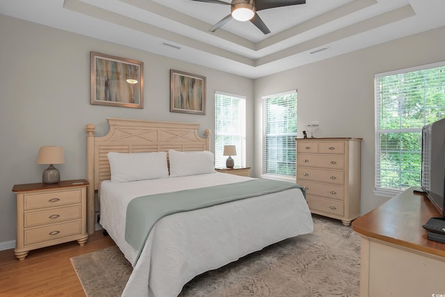 161 Patriot Ln, Pawleys Island, SC 29585 - bedroom featuring a raised ceiling, multiple windows, light wood-type flooring, and ceiling fan