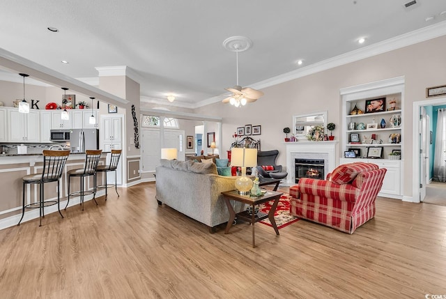 6434 Longwood Dr, Murrells Inlet, SC 29576 - living room featuring light wood finished floors, crown molding, a glass covered fireplace, a ceiling fan, and recessed lighting