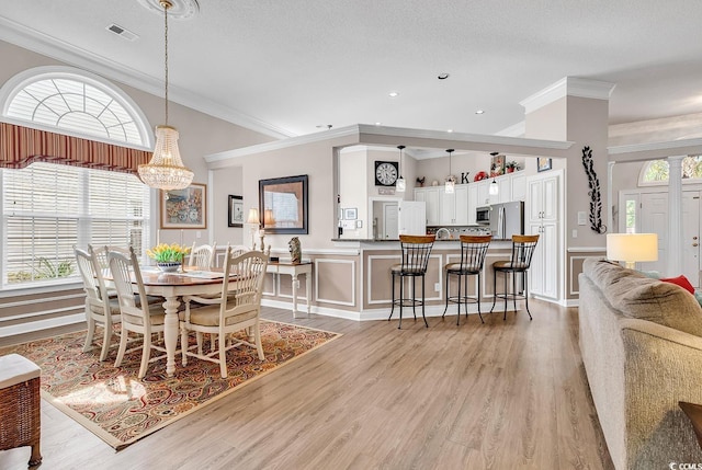 6434 Longwood Dr, Murrells Inlet, SC 29576 - dining area with healthy amount of natural light, wainscoting, light wood finished floors, a decorative wall, and a chandelier