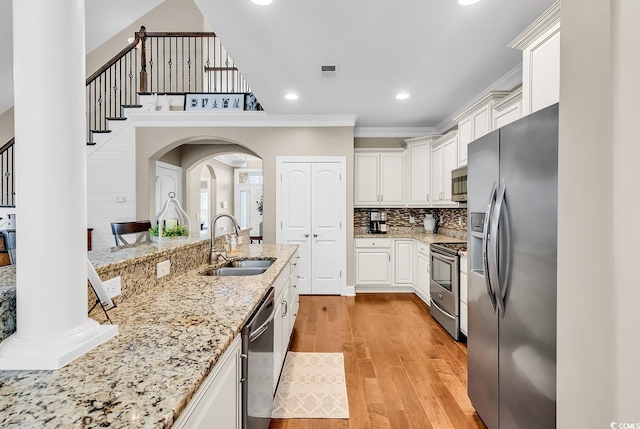 904 Moultrie Cir, Myrtle Beach, SC 29588 - kitchen with stainless steel appliances, light wood-style floors, white cabinetry, light stone counters, and arched walkways