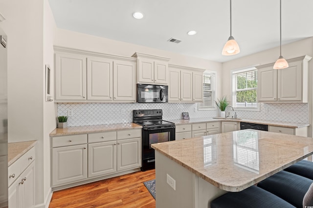 309 Foxpath Loop, Myrtle Beach, SC 29588 - kitchen featuring black appliances, a breakfast bar, light wood-style flooring, backsplash, and hanging light fixtures