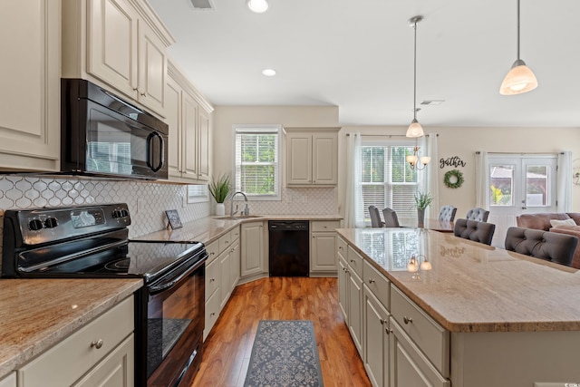 309 Foxpath Loop, Myrtle Beach, SC 29588 - kitchen with black appliances, light wood-type flooring, tasteful backsplash, a center island, and light stone counters