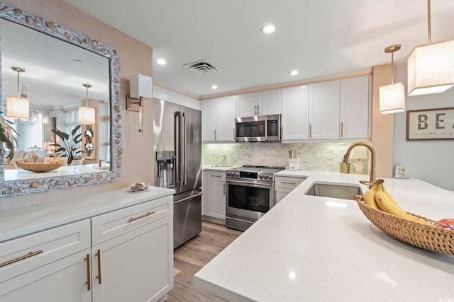 603 S Ocean Blvd Unit 1504, North Myrtle Beach, SC 29582 - kitchen featuring appliances with stainless steel finishes, light wood-style floors, tasteful backsplash, pendant lighting, and white cabinetry