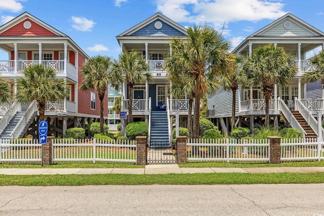 22 Ocean Blvd N, Surfside Beach, SC 29575 - view of front facade featuring stairs, covered porch, a balcony, and a fenced front yard