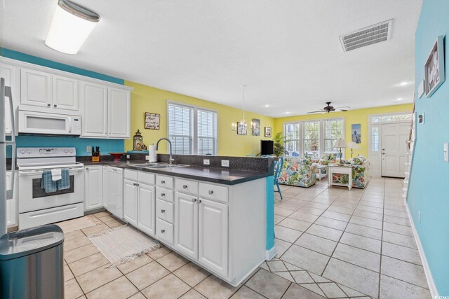 22 Ocean Blvd N, Surfside Beach, SC 29575 - kitchen with white appliances, a peninsula, white cabinets, light tile patterned floors, and recessed lighting