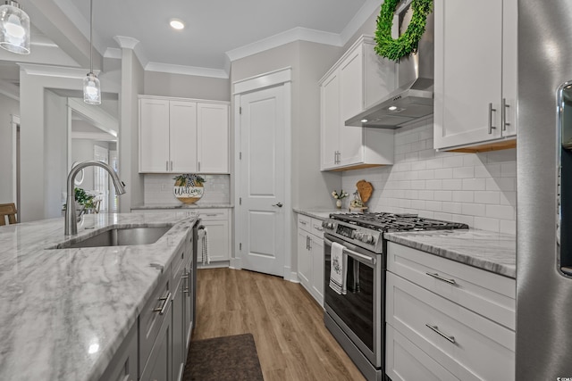 945 Waterbridge Blvd, Myrtle Beach, SC 29579 - kitchen featuring stainless steel gas range, wall chimney exhaust hood, white cabinetry, light wood finished floors, and hanging light fixtures
