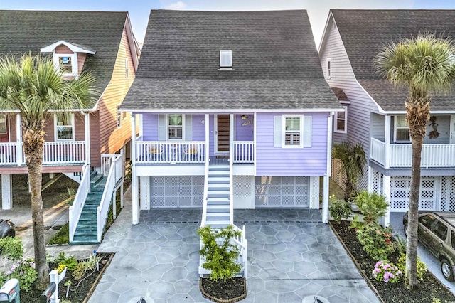4525 Landing Rd, Little River, SC 29566 - coastal inspired home featuring stairs, concrete driveway, a shingled roof, a porch, and an attached garage