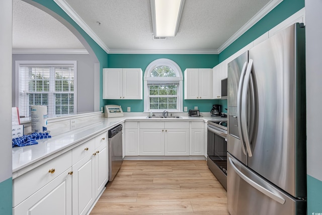 5825 Catalina Dr Unit 125, North Myrtle Beach, SC 29582 - kitchen featuring appliances with stainless steel finishes, a textured ceiling, crown molding, white cabinetry, and light wood-style floors