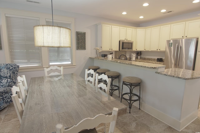 4901 N Market St, North Myrtle Beach, SC 29582 - kitchen featuring appliances with stainless steel finishes, recessed lighting, light stone counters, a peninsula, and a breakfast bar