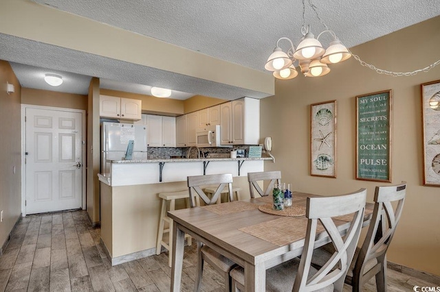 9400 Shore Dr Unit 617, Myrtle Beach, SC 29572 - dining room featuring a chandelier, a textured ceiling, and light wood finished floors