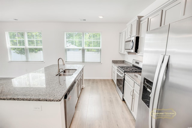 547 Pacific Commons Dr, Surfside Beach, SC 29575 - kitchen featuring appliances with stainless steel finishes, a center island with sink, stone counters, and light wood-type flooring