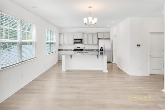 547 Pacific Commons Dr, Surfside Beach, SC 29575 - kitchen with stainless steel appliances, a chandelier, a breakfast bar, light wood finished floors, and an island with sink