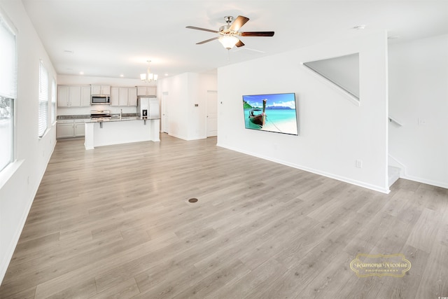 547 Pacific Commons Dr, Surfside Beach, SC 29575 - unfurnished living room featuring ceiling fan, a chandelier, light wood-style flooring, and stairway