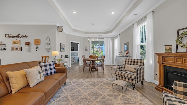 598 Cascade Loop, Little River, SC 29566 - living area with a tray ceiling, wood finished floors, crown molding, a warm lit fireplace, and a chandelier