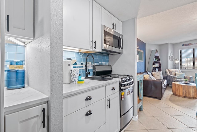 2001 S Ocean Blvd Unit 1408, Myrtle Beach, SC 29577 - kitchen with appliances with stainless steel finishes, backsplash, white cabinetry, open floor plan, and light tile patterned floors