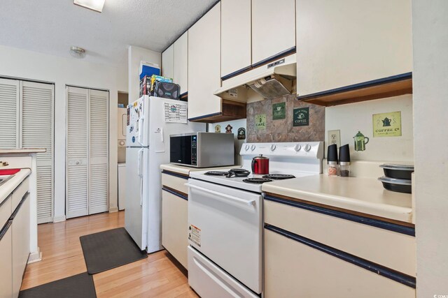 4344 Spa Dr Unit 605, Little River, SC 29566 - kitchen featuring white appliances, under cabinet range hood, white cabinets, light countertops, and light wood-style flooring