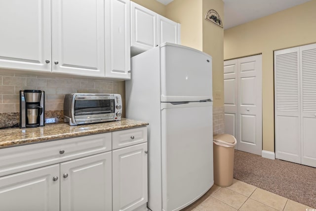 1009 World Tour Blvd Unit 105, Myrtle Beach, SC 29579 - kitchen featuring freestanding refrigerator, light carpet, light tile patterned floors, and white cabinets