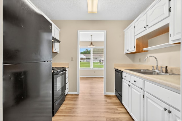 131 Pine Lake Cir, Ocean Isle Beach, NC 28469 - kitchen with black appliances, white cabinetry, light wood finished floors, and a textured ceiling