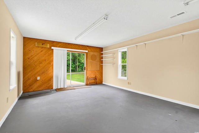 131 Pine Lake Cir, Ocean Isle Beach, NC 28469 - empty room with wood walls, healthy amount of natural light, a textured ceiling, and concrete floors