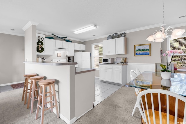 140 S Cove Pl Unit 6C, Pawleys Island, SC 29585 - kitchen with white appliances, ornamental molding, a breakfast bar area, a chandelier, and white cabinetry