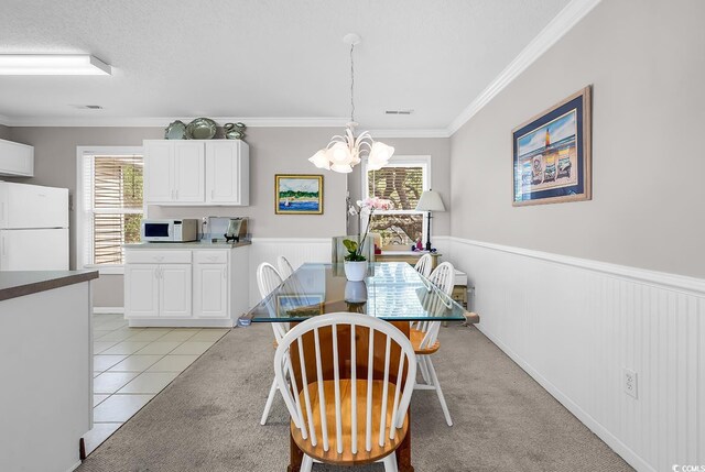 140 S Cove Pl Unit 6C, Pawleys Island, SC 29585 - dining area with a chandelier, ornamental molding, healthy amount of natural light, wainscoting, and light tile patterned flooring