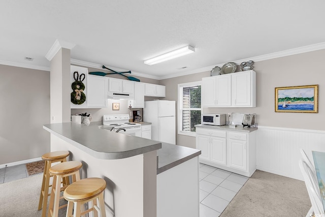 140 S Cove Pl Unit 6C, Pawleys Island, SC 29585 - kitchen with white appliances, ornamental molding, a kitchen bar, light tile patterned floors, and white cabinets