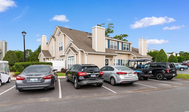 503 20th Ave N Unit 29-C, North Myrtle Beach, SC 29582 - view of property with a chimney, uncovered parking, and a shingled roof