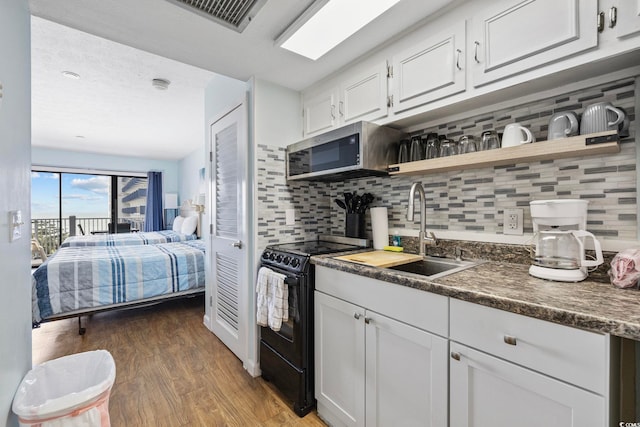 2000 S Ocean Blvd Unit V405, Myrtle Beach, SC 29577 - kitchen with black electric range oven, stainless steel microwave, open shelves, light wood-type flooring, and tasteful backsplash