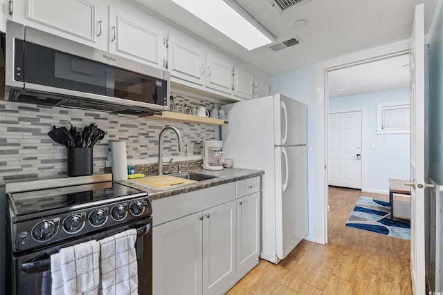 2000 S Ocean Blvd Unit V405, Myrtle Beach, SC 29577 - kitchen with electric stove, stainless steel microwave, freestanding refrigerator, white cabinetry, and decorative backsplash