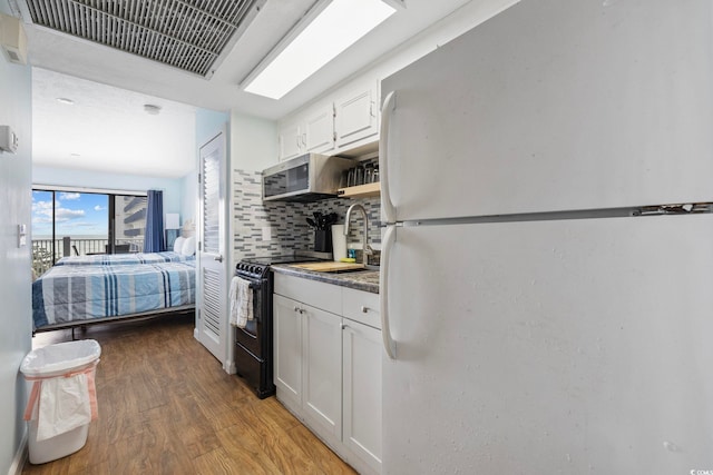 2000 S Ocean Blvd Unit V405, Myrtle Beach, SC 29577 - kitchen featuring freestanding refrigerator, black range with electric cooktop, light wood finished floors, white cabinetry, and decorative backsplash