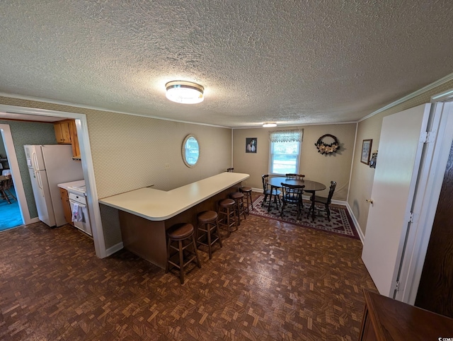 5370 Miracle Ln, Conway, SC 29526 - kitchen featuring ornamental molding, freestanding refrigerator, a kitchen bar, light countertops, and a peninsula