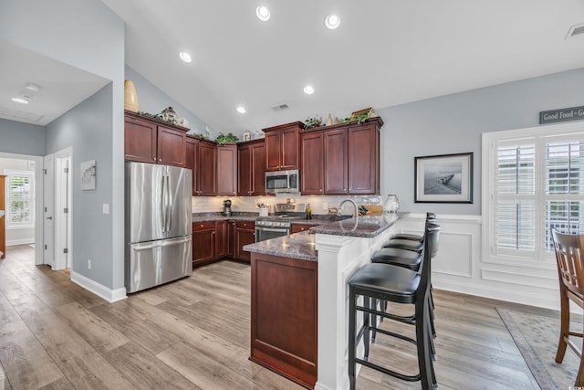 1413 Cottage Cove Cir N, Myrtle Beach, SC 29582 - kitchen with appliances with stainless steel finishes, a peninsula, light wood-type flooring, a kitchen breakfast bar, and wainscoting