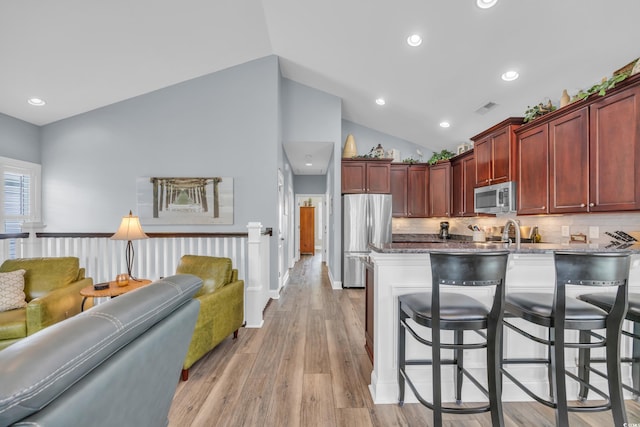 1413 Cottage Cove Cir N, Myrtle Beach, SC 29582 - kitchen with stainless steel appliances, reddish brown cabinets, a kitchen bar, recessed lighting, and tasteful backsplash