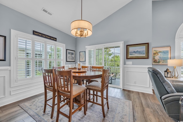 1413 Cottage Cove Cir N, Myrtle Beach, SC 29582 - dining room with a chandelier, high vaulted ceiling, a decorative wall, wainscoting, and wood finished floors