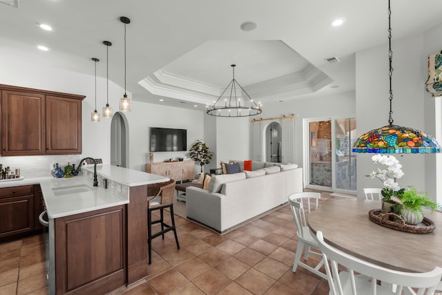 9737 Catalonia Ct, Myrtle Beach, SC 29579 - kitchen featuring a kitchen breakfast bar, light countertops, arched walkways, a tray ceiling, and a peninsula