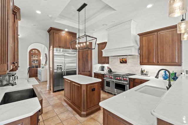 9737 Catalonia Ct, Myrtle Beach, SC 29579 - kitchen with high quality appliances, custom range hood, backsplash, light tile patterned flooring, and a raised ceiling